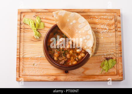 Putuk / Piti - traditionelle armenische Kichererbsen und Lammeintopf in einem Tontopf mit Fladenbrot bedeckt serviert. Stockfoto