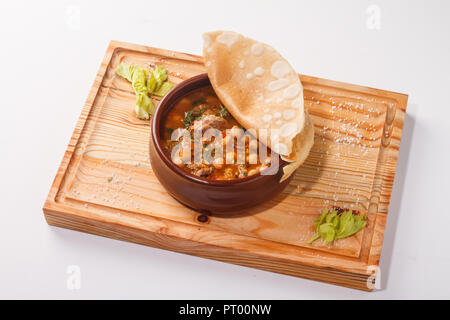 Putuk / Piti - traditionelle armenische Kichererbsen und Lammeintopf in einem Tontopf mit Fladenbrot bedeckt serviert. Stockfoto