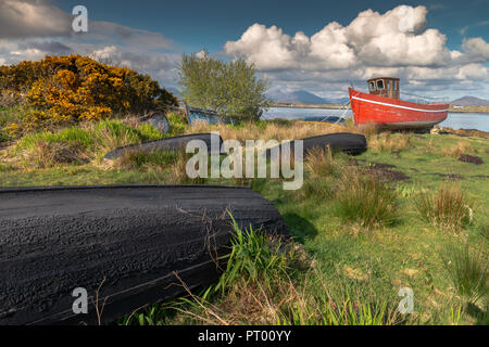 Roundstone, Connemara, Galway, Irland, 04/2018, heruntergekommene Fischerboote links nach Verfall neben der Bucht von Connemara. Stockfoto