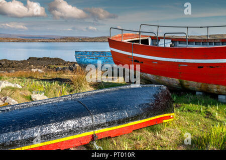 Roundstone, Connemara, Galway, Irland, 04/2018, heruntergekommene Fischerboote links nach Verfall neben der Bucht von Connemara. Stockfoto