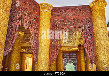 YANGON, MYANMAR - 27. FEBRUAR 2018: Die dekorativen Elemente von Kassapa Buddha Bild Haus: komplexe Verputz auf Spalten und aus Holz geschnitzte Lattice zw. Stockfoto