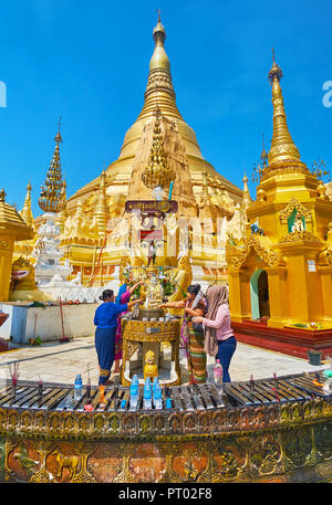 YANGON, MYANMAR - 27. FEBRUAR 2018: Die Buddhistische Anhänger das Ritual der gießt Wasser auf die Statue des Buddha in der Shwedagon Pagode mit brennenden führt Ca Stockfoto