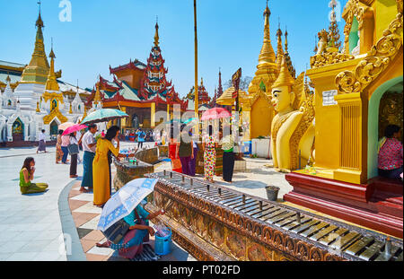 YANGON, MYANMAR - 27. FEBRUAR 2018: Die buddhistische Anbeter mit Kerzen und Räucherstäbchen auf dem Altar der Shwedagon Pagode, am 27. Februar in Yango Stockfoto