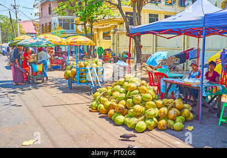 YANGON, MYANMAR - Februar 27, 2018: Der Haufen grüne Kokosnüsse an der Stall der burmesischen Bauern in Gyar Tawya Street Market, am 27. Februar in Yangon. Stockfoto