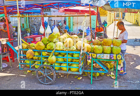 YANGON, MYANMAR - 27. FEBRUAR 2018: die Karre mit grünen Kokosnüssen in Gyar Tawya Street Market, am 27. Februar in Yangon. Stockfoto