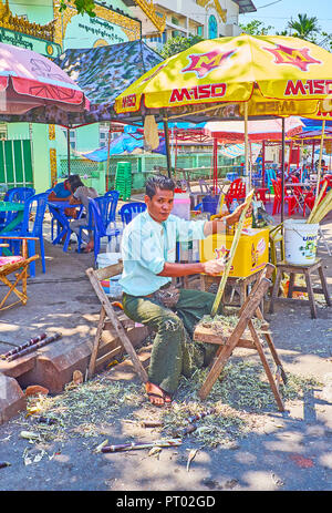 YANGON, MYANMAR - Februar 27, 2018: Der Anbieter schalen Zuckerrohr für die Zubereitung von Saft in Gyar Tawya Street Market, am 27. Februar in Yangon. Stockfoto