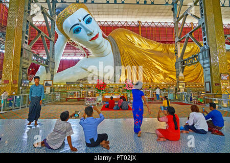 YANGON, MYANMAR - 27. FEBRUAR 2018: die Anbeter der Bilder zu machen, auf dem Boden sitzend vor chaukhtatgyi Buddha Bild, am 27. Februar in Y Stockfoto