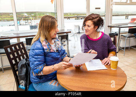 Zwei Frauen Unterzeichnung Formen in einem Cafe, Irland Stockfoto