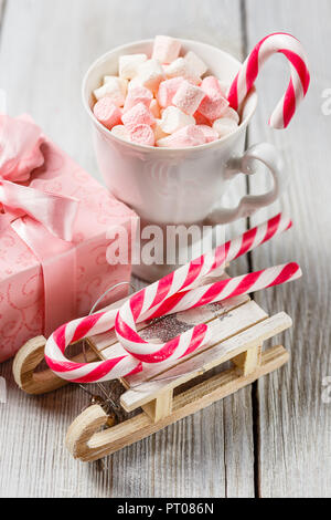 Weiß und rosa Marshmallows in eine Schale, Weihnachten Zuckerstangen und Spielzeug Schlitten auf einem weißen Tisch. Thema Weihnachten. Stockfoto