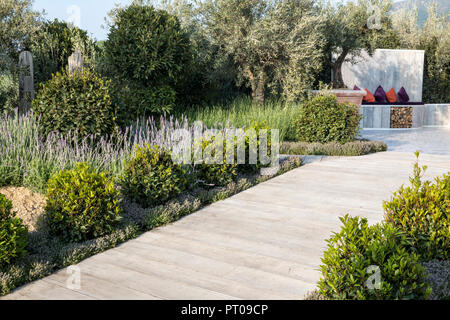 Mediterraner Garten Holzterrassenweg gesäumt von Prunus lusitanica unterpflanzt mit Thymus- und Lavandula-Olivenbäumen mit Sitzplätzen im Freien UK Stockfoto