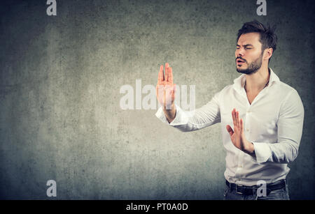 Junge Augen Geschäftsmann outstretching Hände und Suchen in der Dunkelheit auf grauem Hintergrund Stockfoto