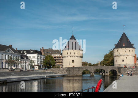 Kortrijk, Flandern, Belgien - 17. September 2018: Iconic aus hellem Backstein Broeltürmen auf der Brücke über den Fluss Lys unter blauem Himmel. Menschen und Gebäude auf der Seite Stockfoto