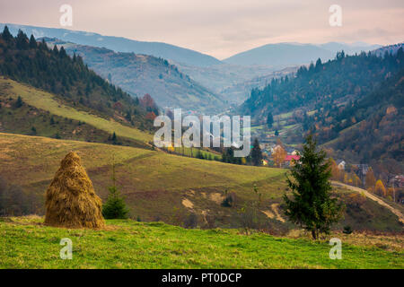 Reizende Landschaft in den Bergen an einem düsteren Tag. Dorf im Tal. Riesige ridge in der Ferne. Stockfoto