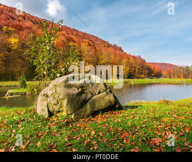 Boulder am Ufer eines Sees. schöne Herbstlandschaft im Park. die bewaldeten Hügel im Herbst Farben Stockfoto