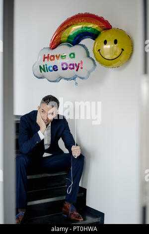 Unternehmer sitzen auf der Treppe holding Ballon Stockfoto