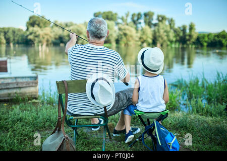 Rückansicht der Großvater und Enkel Angeln am Seeufer Stockfoto