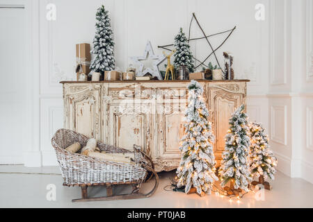 Weihnachtsdekoration auf alten Vintage alte Kommode Kommode. Handarbeit Handwerk Geschenke, Kerzen und ein Baum im Hintergrund Stockfotografie