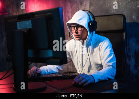 Professionelle boy Gamer spielt in Video Games, eSports Turnier oder im Internet Café. Er trägt Kopfhörer und spricht Befehle in das Mikrofon. Stockfoto