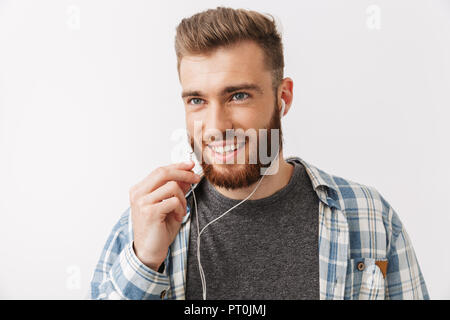 Portrait eines glücklichen jungen bärtigen Mann stehend über Weiß isoliert, sprechen über Kopfhörer Stockfoto