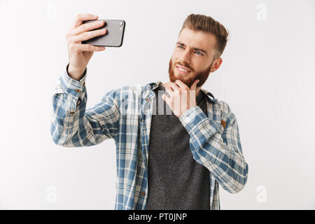 Porträt einer fröhlicher junger bärtiger Mann stehend über Weiß isoliert, wobei ein selfie Stockfoto