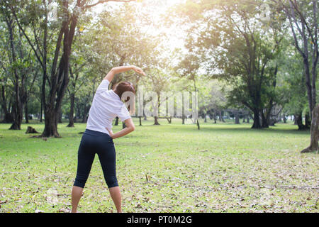 Junge weibliche Übung im Park im Morgen, Frau trainieren und entspannen, bevor der fitness training, warm up Konzept Stockfoto