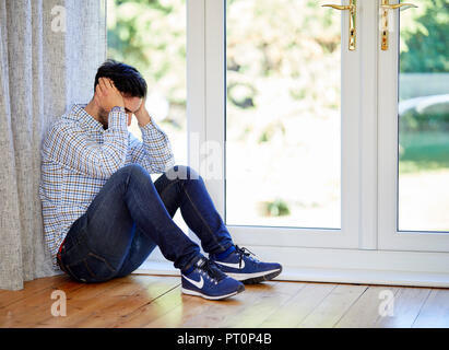 Betonte Mann saß auf dem Boden Stockfoto