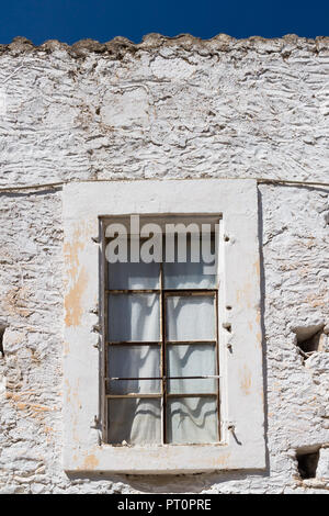 Geschlossenes Fenster eines alten Hauses. Breiten Rahmen und Vorhänge in die Fenster. Steinmauer weiß lackiert. Gewellte Rand des Daches. Tief blauen Himmel. Traditionelle moun Stockfoto