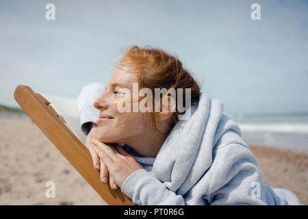 Lächelnde Frau im Liegestuhl liegend, genießen Sie ein Sonnenbad am Strand Stockfoto