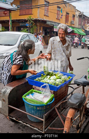 Ältere Frau mit gebogenen Dorn verkauf Limes aus ihrem Rikscha. Bangkok, Thailand. Stockfoto