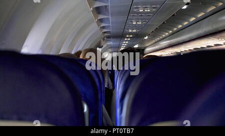 Candid shot zwischen den Sitzen der Passagiere sitzen im Flugzeug unterwegs. Stockfoto