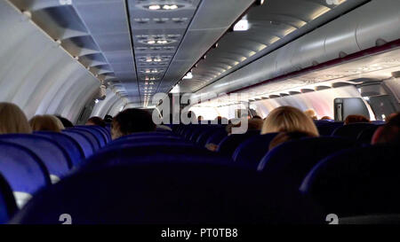 Candid shot zwischen den Sitzen der Passagiere sitzen im Flugzeug unterwegs. Stockfoto