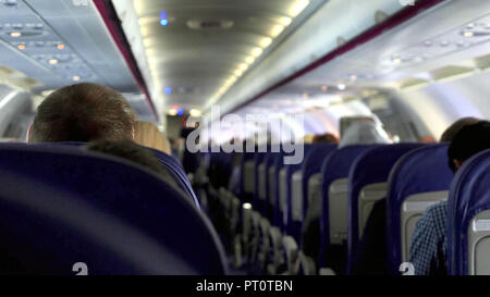 Candid shot zwischen den Sitzen der Passagiere sitzen im Flugzeug unterwegs. Stockfoto