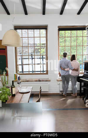 Reifes Paar stehend in der komfortablen Loft, schauen aus dem Fenster, Rückansicht Stockfoto