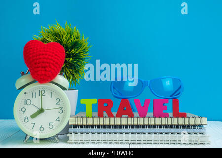 Reisen Buchstaben text und Notebook Papier, Wecker und wenig Deko Baum in weiße Vase auf hölzernen Hintergrund, Reise Urlaub Konzept Idee. Stockfoto