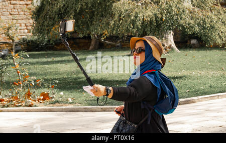 Istanbul, Türkei, September 2018: Junge etwas Übergewicht asiatische Frau mit Stroh Hut und Sonnenbrille lächelnd macht einen selfie in einem türkischen Garten Stockfoto