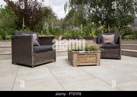 Moderne versunkene Terrasse Garten Hochbett Blumenbeete Porzellan Steinpflaster auf Terrasse mit hölzernen Kiste Pflanzgefäß Gartenstühle Gartenmöbel UK Stockfoto