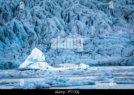 Ein großer Eisberg schweben in der Gletscherlagune Jokulsarlon von, Island, leuchtet durch die Sonne, während der Vordergrund und Hintergrund Gletscher Eisberge sind Alle Stockfoto