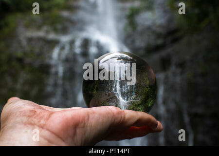 Wasserfall im Glas Ball oder Kugel in der Handfläche der Wanderer in der Hand gefangen Stockfoto