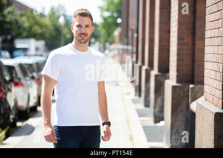 Porträt von einem gutaussehenden jungen Mann stehen auf Bürgersteig Stockfoto