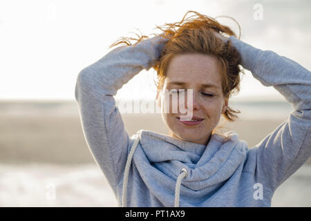 Rothaarige Frau genießen die frische Luft am Strand Stockfoto