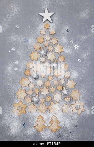 Sternförmige Kekse und Christbaumkugeln bilden Weihnachtsbaum auf grauem Hintergrund Stockfoto