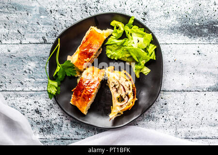 Swiss roll, Blätterteig mit Wurst, Fleisch, Käse, Zwiebel, Petersilie und Salat auf Teller Stockfoto