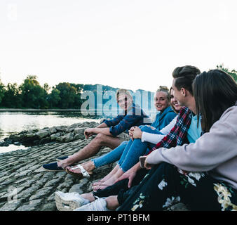 Gruppe von Freunden am Fluss sitzen am Abend Stockfoto