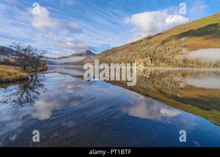 Reflexionen in Llyn Gwynant an einem nebligen Morgen im glaslyn Tal nach Westen mit Yr Aran Berg im Hintergrund Snowdonia National Park Stockfoto