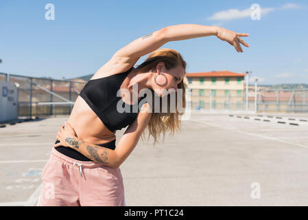 Tätowierte junge Frau zu tun Stretching Übungen Stockfoto