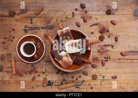 Hausgemachte Espresso und weiße Schokolade Eis am Stiel mit winterlichen Gewürzen und Tasse Espresso auf Holz- Hintergrund Stockfoto