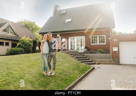 Lächelnd reifes Paar im Garten ihres Hauses umarmt Stockfoto