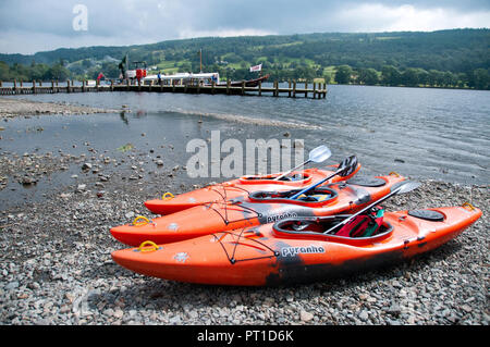 Drei bunte Kanus zog am Strand mit den Vintage Dampf Gondel im Hintergrund auf Coniston Water. Stockfoto