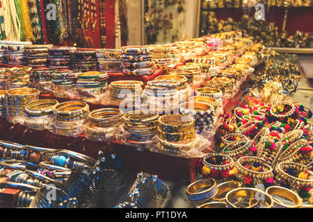 Traditionelle indische Armreifen und Armbänder an der Straße Markt in Udaipur, Rajasthan, Indien. Schmuck aus vergoldetem Metall mit bunten Steinen Stockfoto