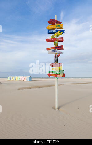 Wegweiser den Weg zu den internationalen Standorten am Strand von Berck-Plage, Frankreich, bunten Beach Cabins im Hintergrund. Stockfoto